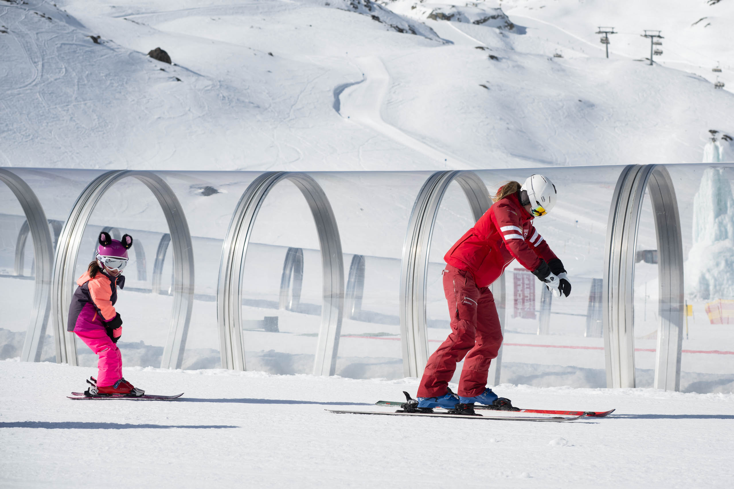 Eine Schneesportlehrerin zeigt den Kindern eine Übung vor